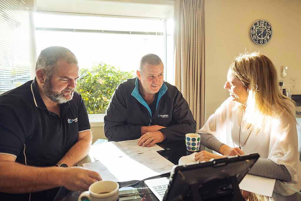 Coughlan Homes team reviewing house plans around a table